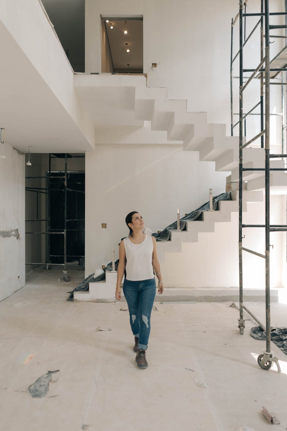Nayara Barros caminhando numa obra, ao lado de uma escada em construção